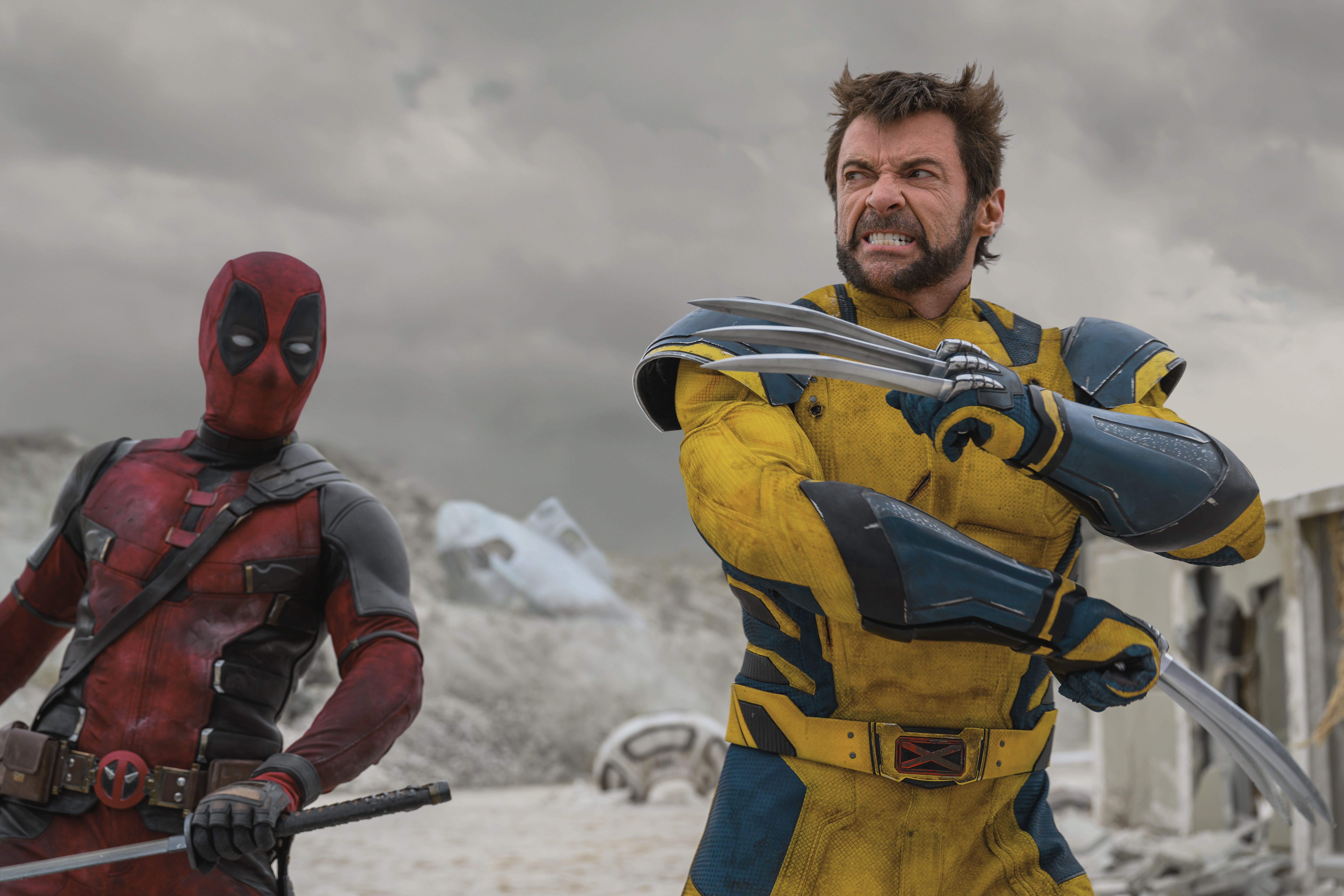 Wolverine coloca as garras com os braços sobre o peito enquanto Deadpool olha para a espada na mão em uma cena de Deadpool & Wolverine