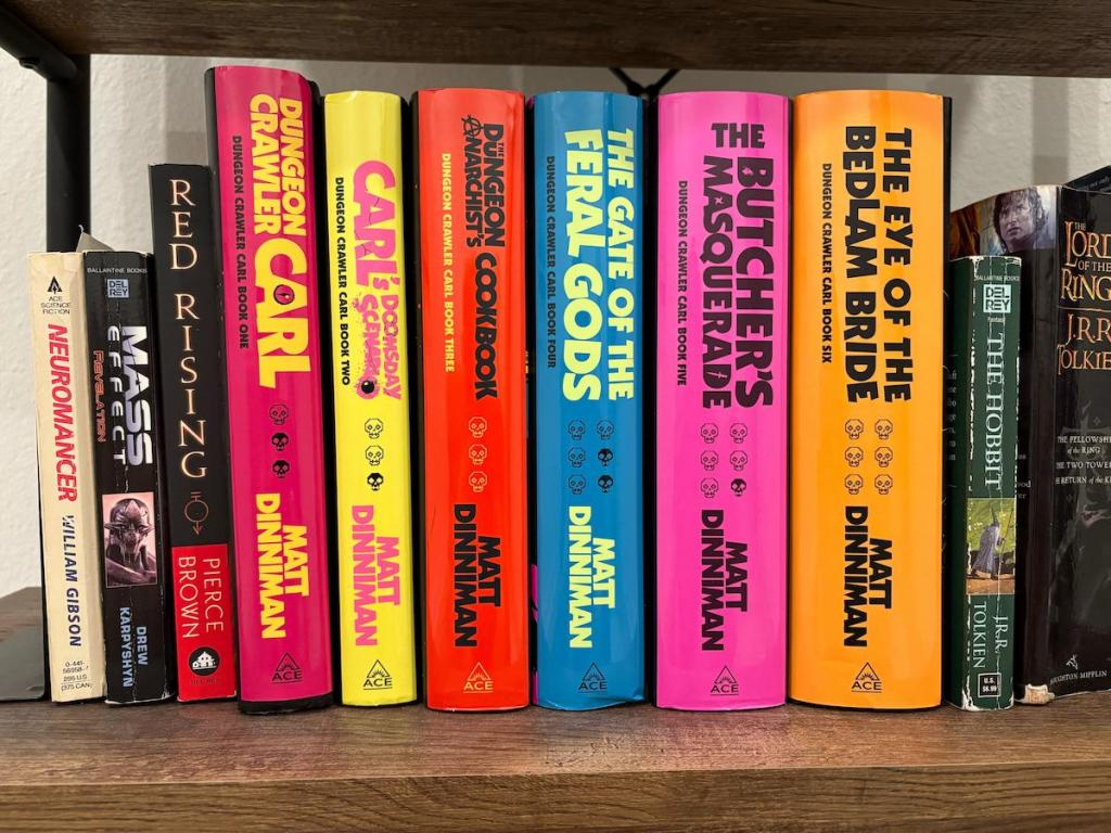 Uma fotografia dos livros de Crawler Carl de masmorra em uma prateleira. Todos eles têm textos e espinhos de cores vivas.