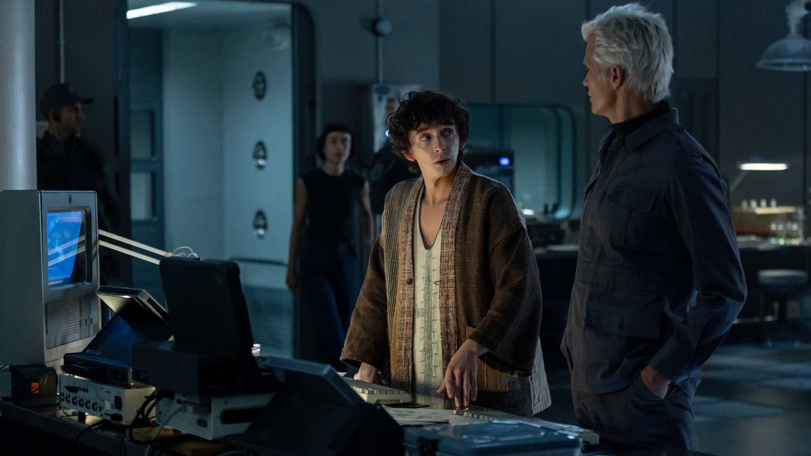 O garoto Kavalier fala com o cientista sintético Kirsh como Wendy, um híbrido, se aproxima de uma distância.