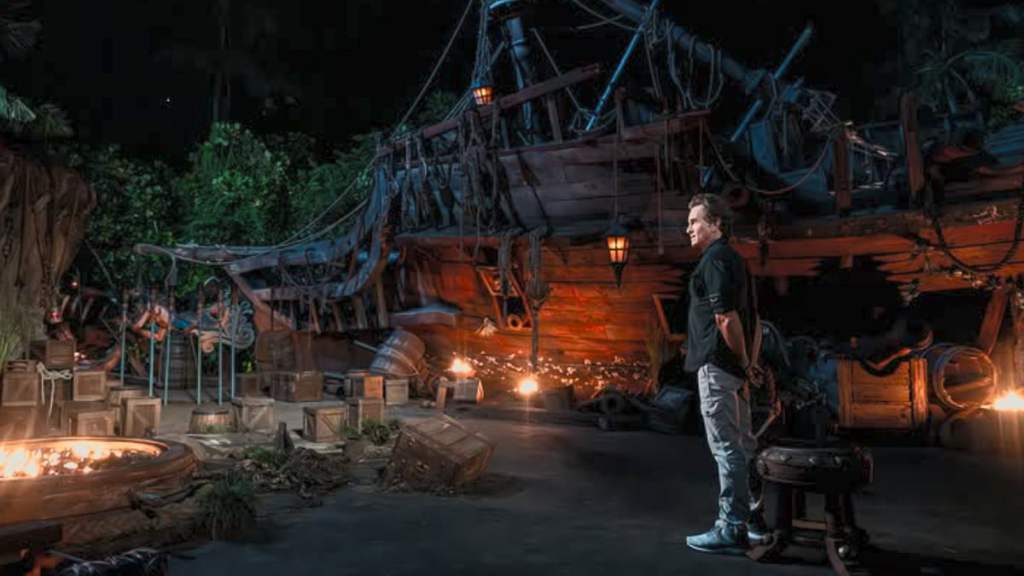 Jeff Probst em pé em frente a um naufrágio no Conselho Tribal em Survivor