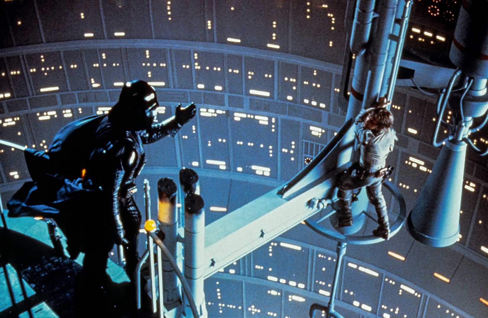 Darth Vader estende a mão em direção a Luke Skywalker (Mark Hamill), que está subindo até o fim de um pórtico, no Império Strikes de volta