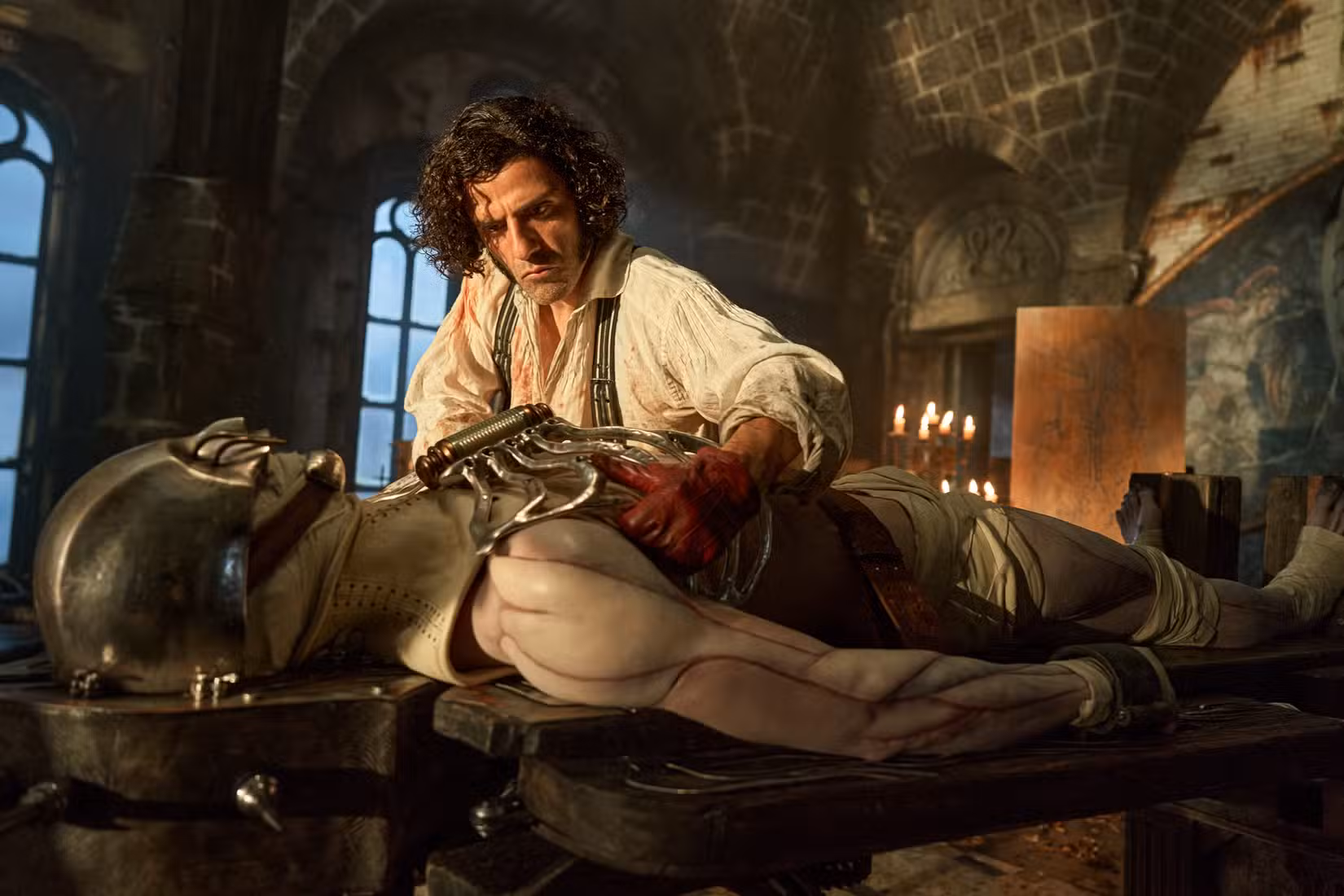 Foto do filme de Frankenstein: Victor fica de costas para a câmera, enquanto sua criação está sobre a mesa, ainda sem ganhar vida