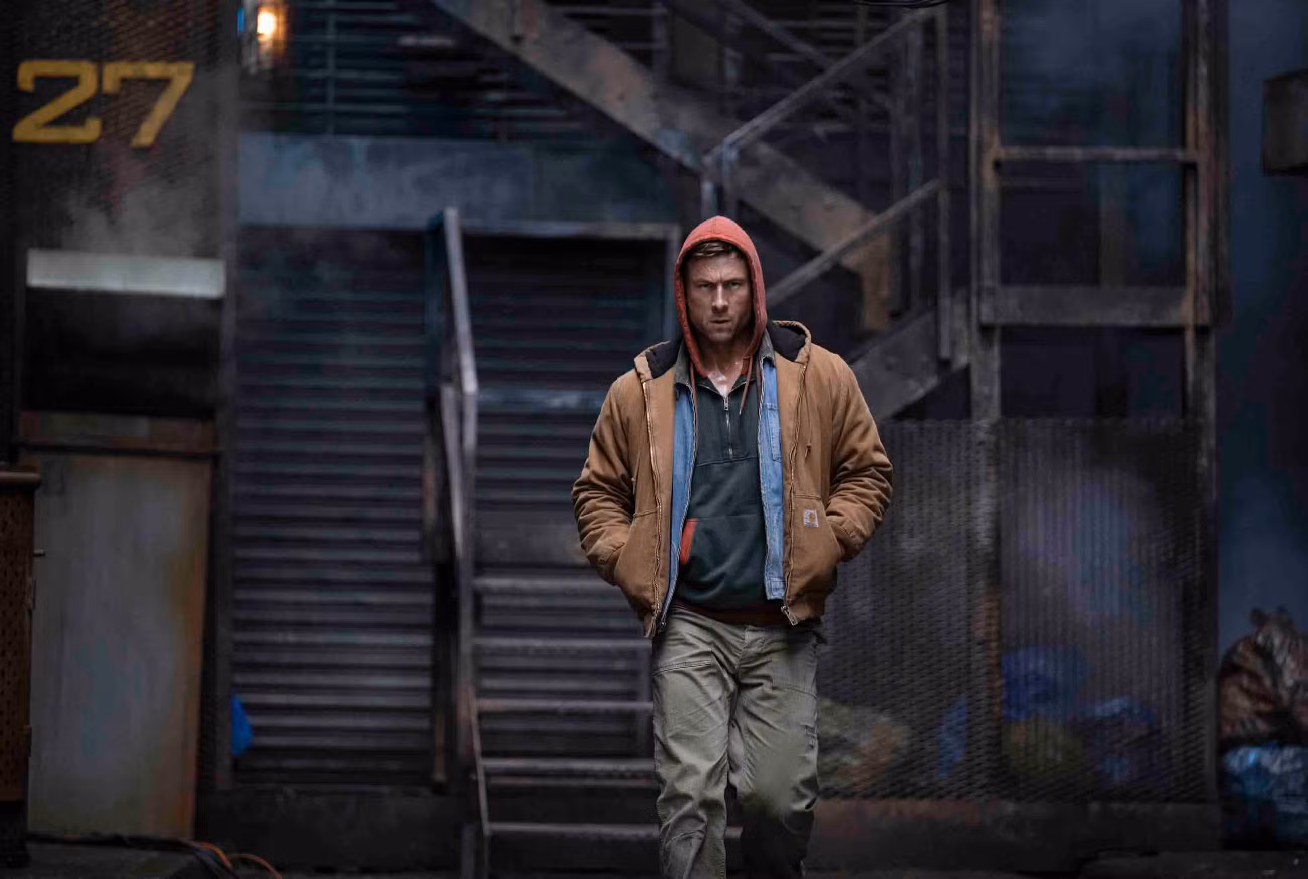 Glen Powell caminha por um beco em The Running Man