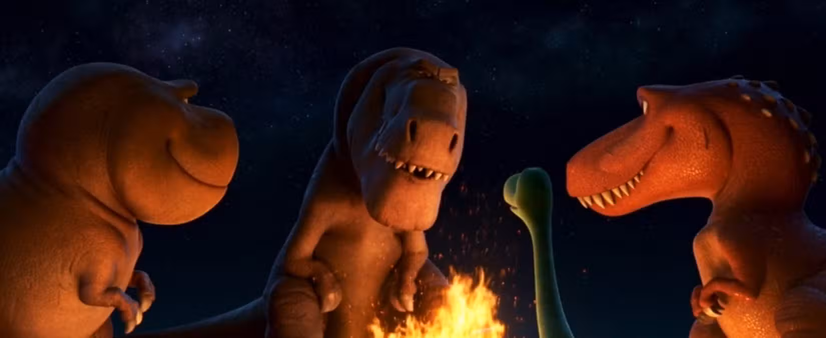 Vários T. rexes e um dinossauro menor se reúnem ao redor de uma fogueira à noite em uma cena de O Bom Dinossauro.