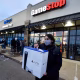 Um homem usando máscara sai da GameStop com o novo PlayStation 5