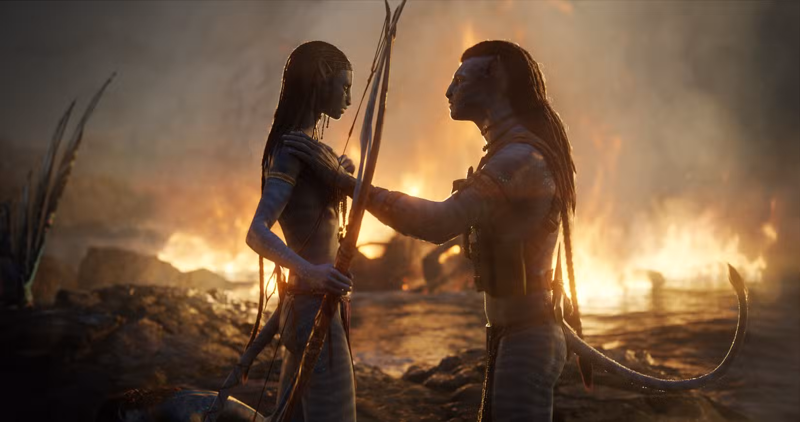 Jake Sully e Neytiri se consolam após a batalha, com um fogo crepitando atrás deles sobre a água em Avatar: The Way of Water