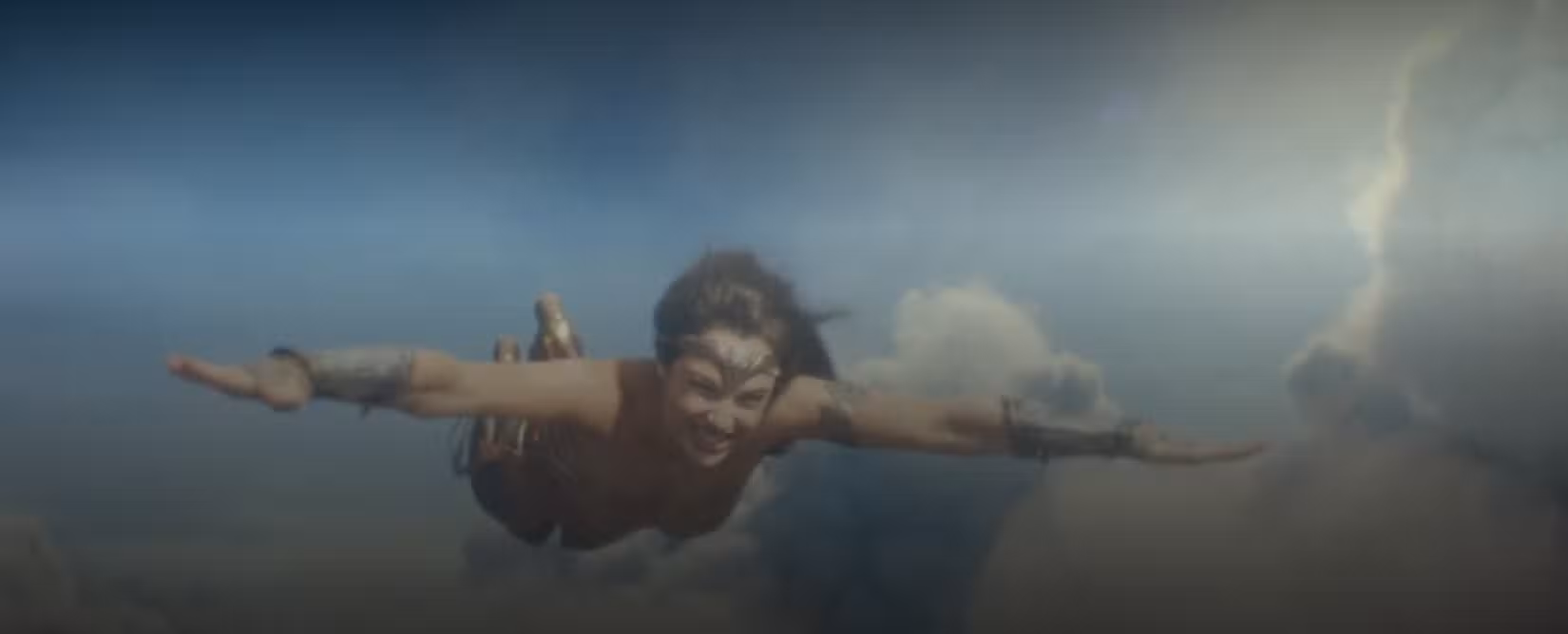 Em uma cena de Mulher Maravilha 1984, Diana (Gal Gadot) voa pelo ar, seguindo o conselho de seu falecido namorado sobre como pilotar-se como um jato