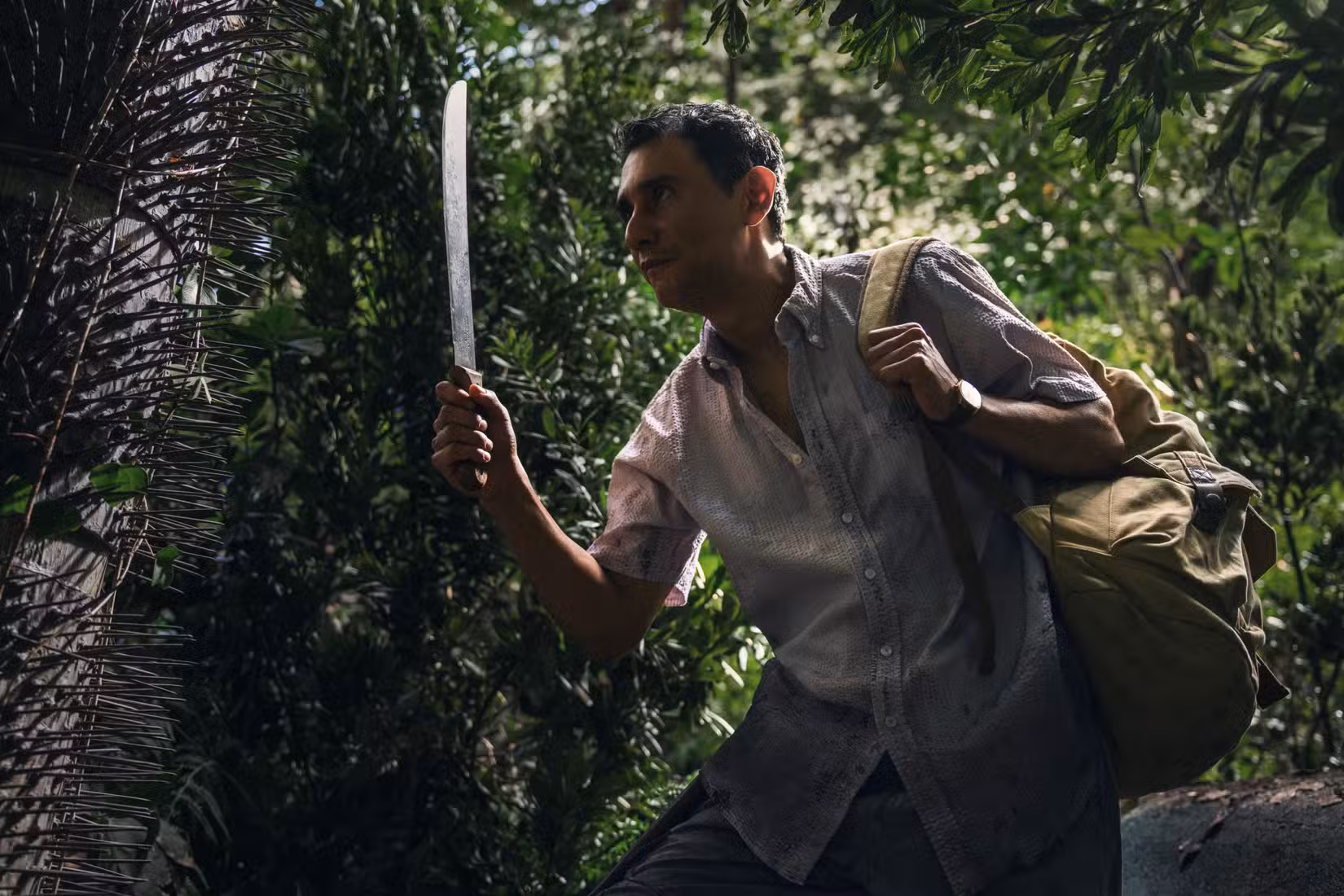 Manousos (Carlos-Manuel Vesga), segurando um facão, abre caminho suado pela selva em Pluribus