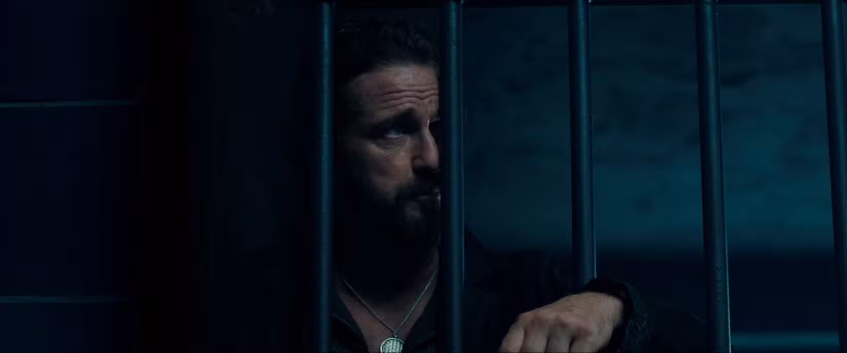 Gerard Butler, no papel de um assassino astuto, vive em uma cela escura de prisão em uma cena de Copshop (2021).