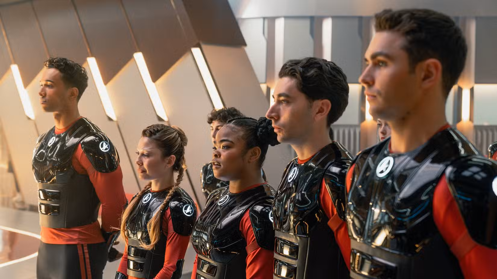 Caleb mir (sandro rosta), Genesis Lythe (Bella Shepard), Sam (Kerrice Brookks), OCAM ADAL (Romo Carere) e Darem Reymi (George Hawkins) formam uma fila de armadura na Starflet Academy