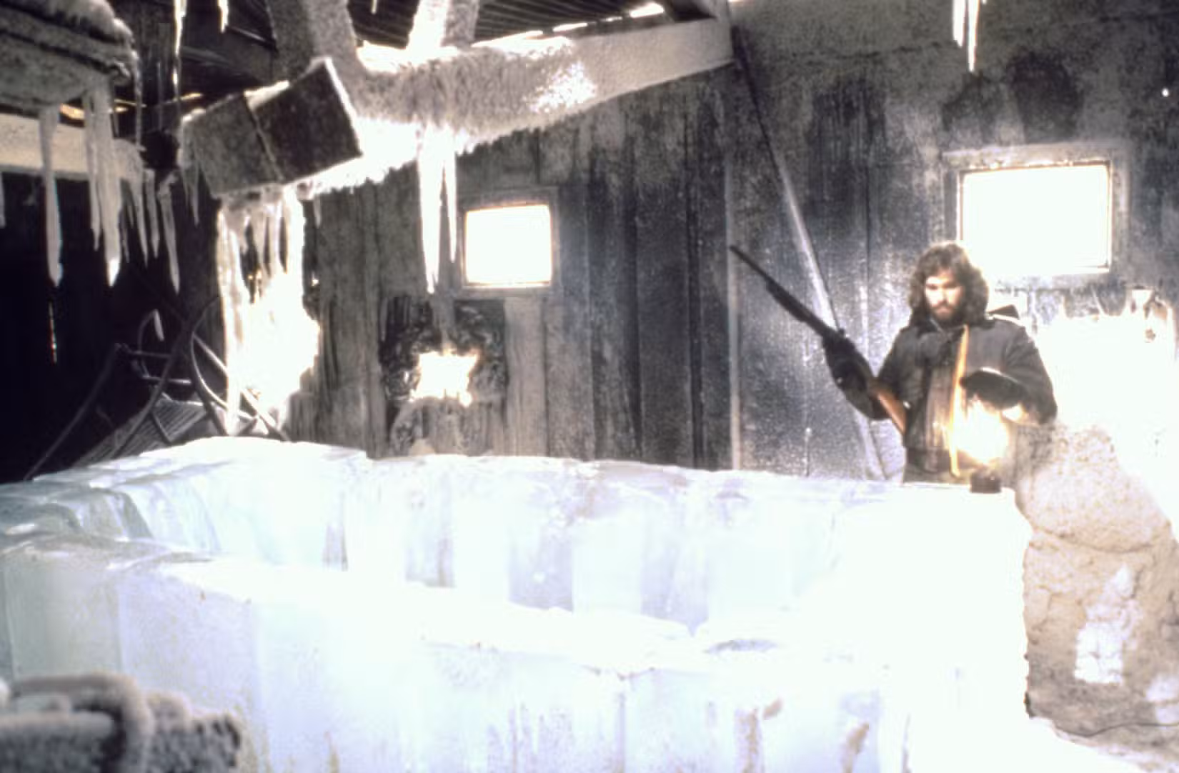 MacReady segura um rifle enquanto olha para o posto avançado norueguês em The Thing, de John Carpenter