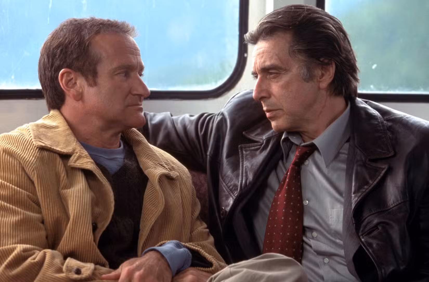 Al Pacino e Robin Williams sentam-se desconfortavelmente próximos e parecem confrontadores em uma cena do filme Insônia, de Christopher Nolan, de 2002