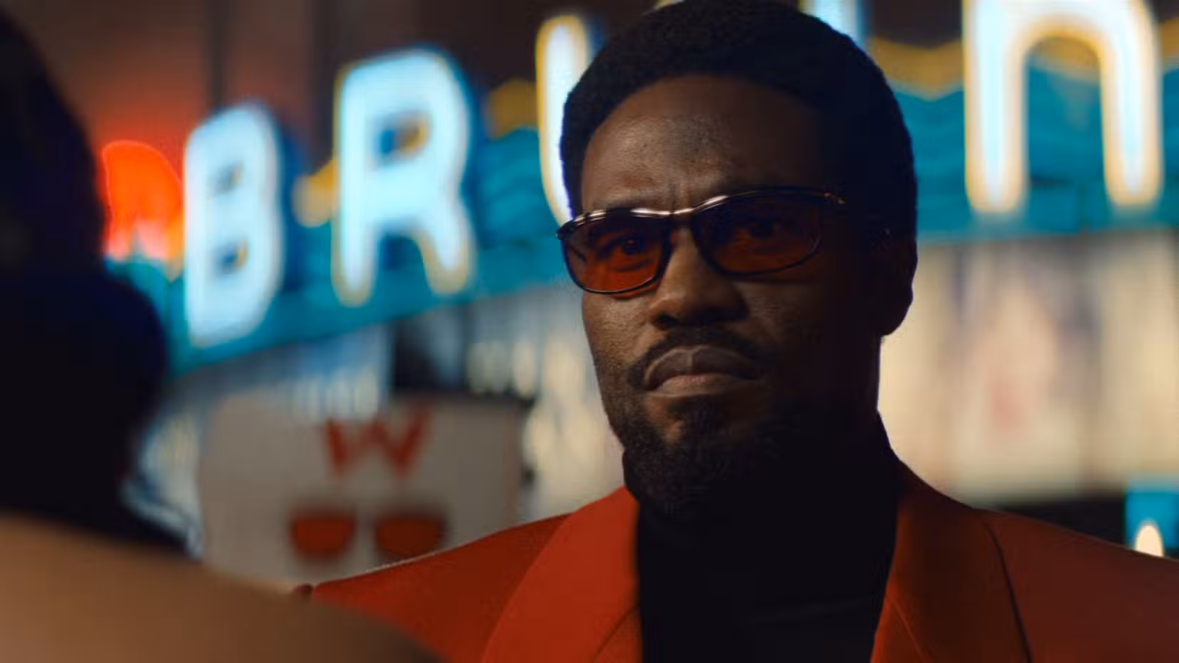 Yahya Abdul-Mateen II como Simon Williams, com óculos escuros vermelhos e paletó vermelho, em Marvel's Wonder Man