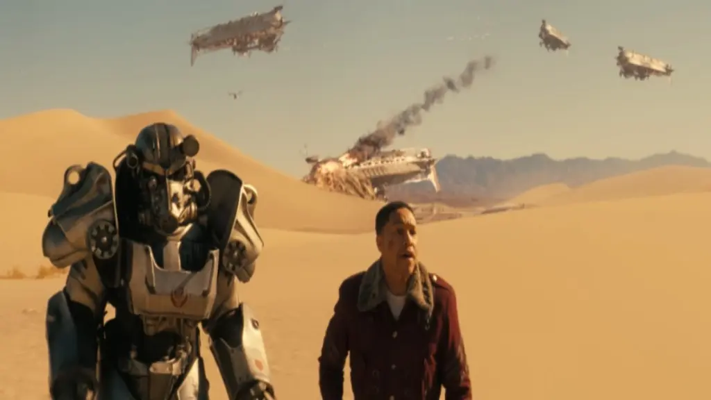Maximus e Thaddeus correndo no deserto com aeronaves caindo atrás deles
