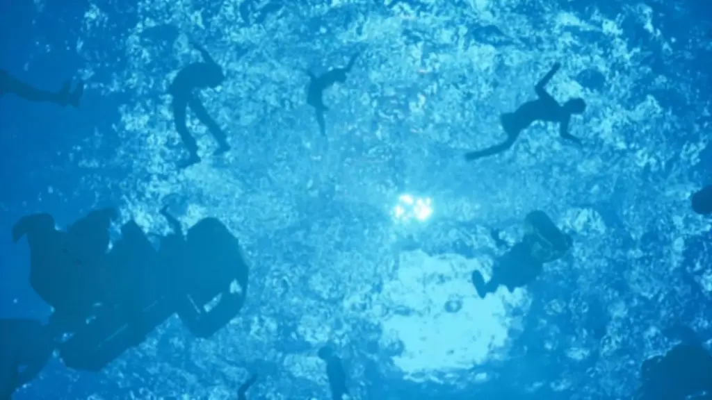 Uma cena em que o protagonista afunda no oceano com corpos flutuando em direção à superfície