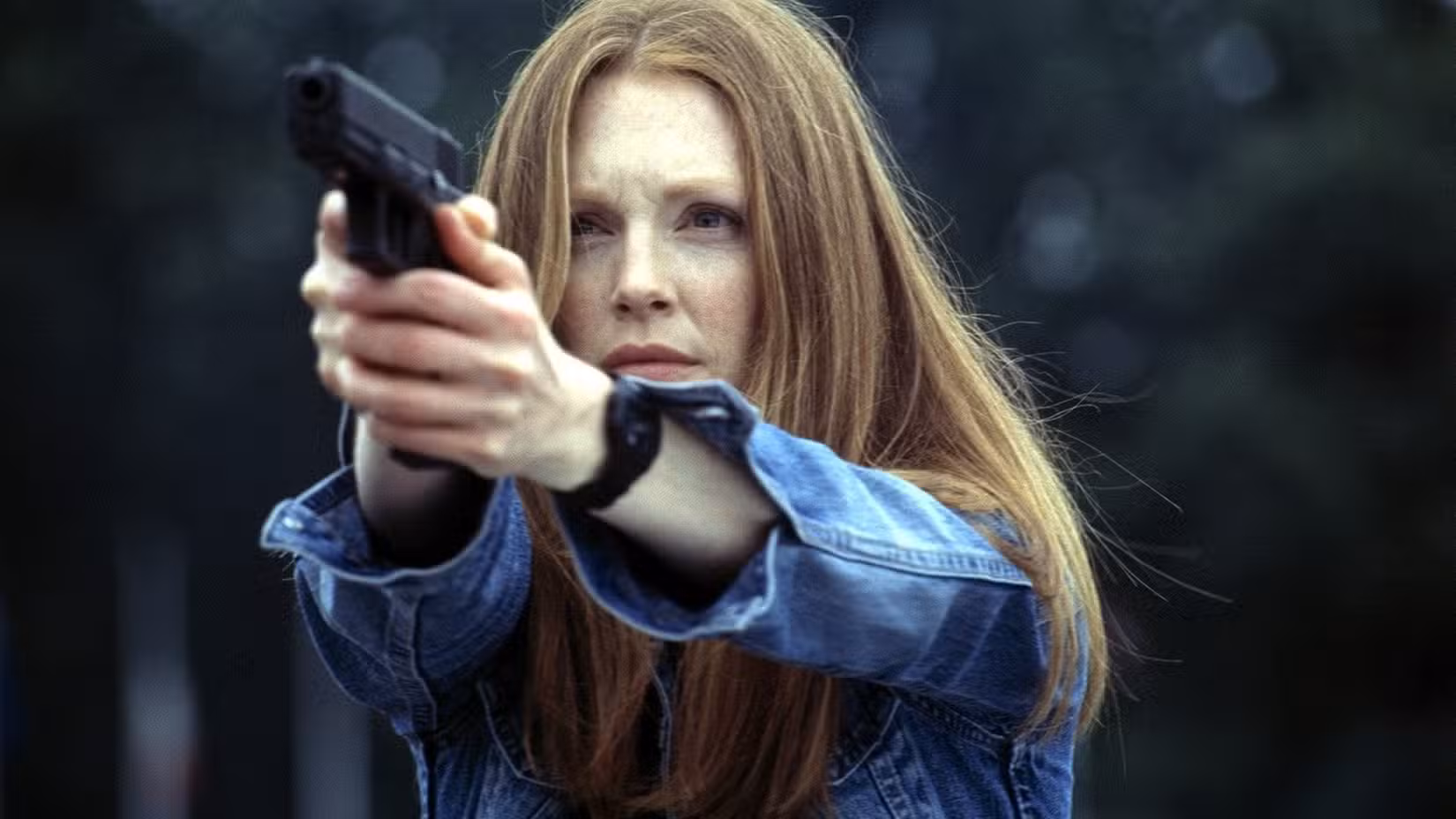 Clarice Starling (Julianne Moore) aponta uma arma ao ar livre para um alvo fora da tela em uma cena de Hannibal (2001).