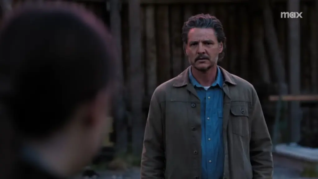 Pedro Pascal interpretando Joel Miller em TLOU com a nuca de Ellie fora de foco em primeiro plano