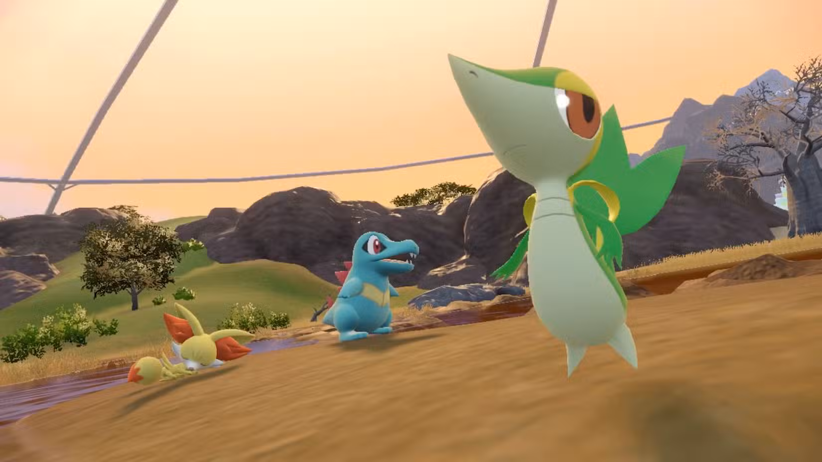 Totodile, Snivy e Fennekin no DLC Pokémon Scarlet e Violet. Eles estão todos em um campo gramado.