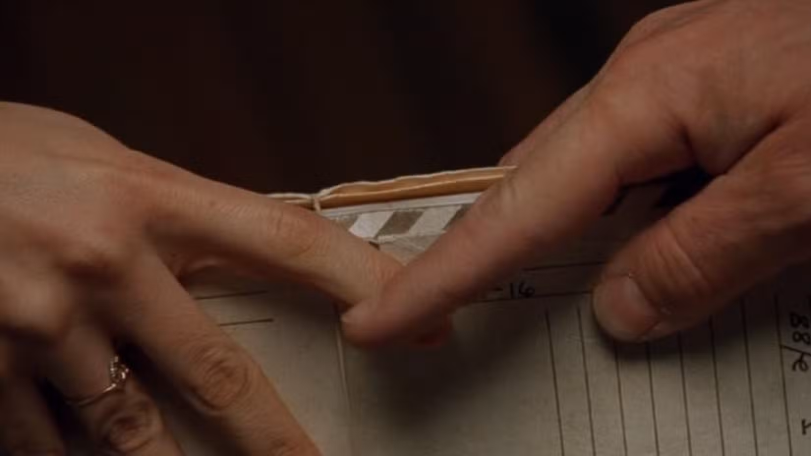 Lecter toca sutilmente a mão da Agente Starling enquanto ela lhe entrega alguns documentos.