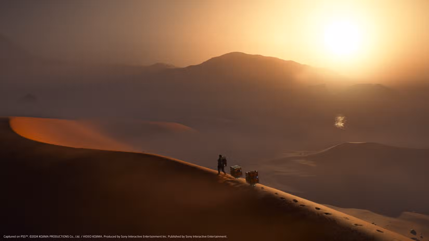 Um plano geral de Sam Bridges caminhando no topo de uma duna no deserto em Death Stranding 2