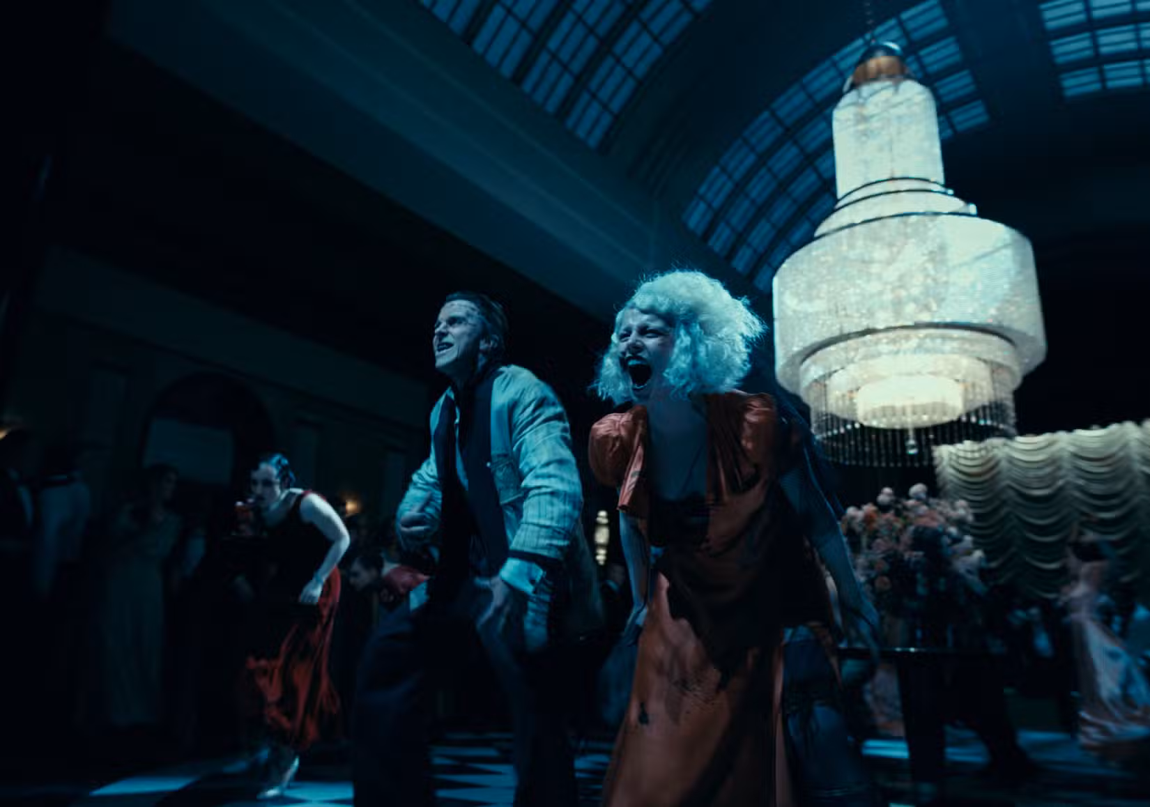 Frankenstein (Christian Bale) e Ida (Jessie Buckley) gritam enquanto lideram um esquadrão de dançarinos em uma dança curvada e cambaleante em A Noiva!