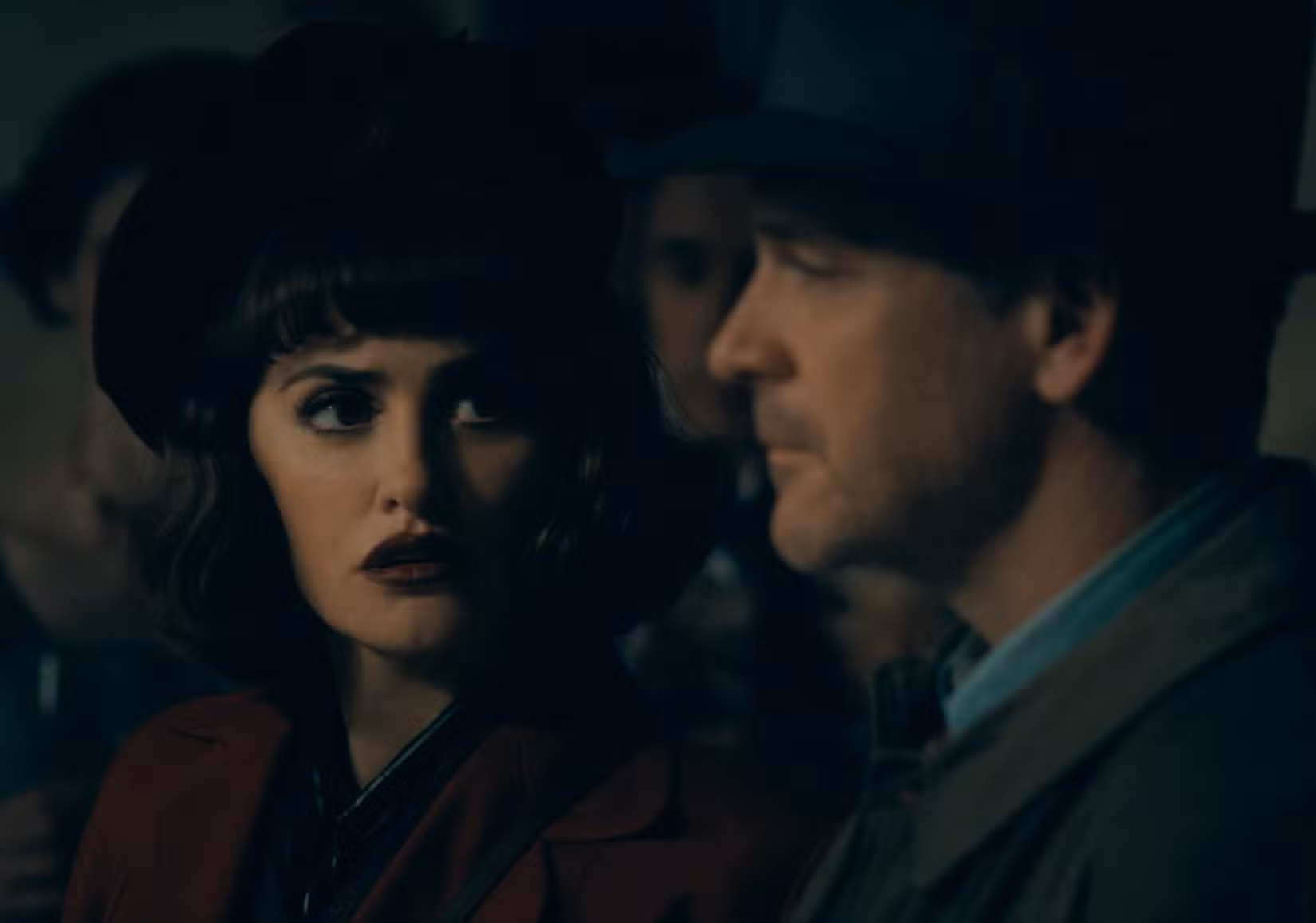 Myrna (Penélope Cruz), uma mulher de cabelos escuros e boina com uma expressão traída no rosto, está sentada em um carro à noite com Jake Wiles (Peter Sarsgaard) em A Noiva!