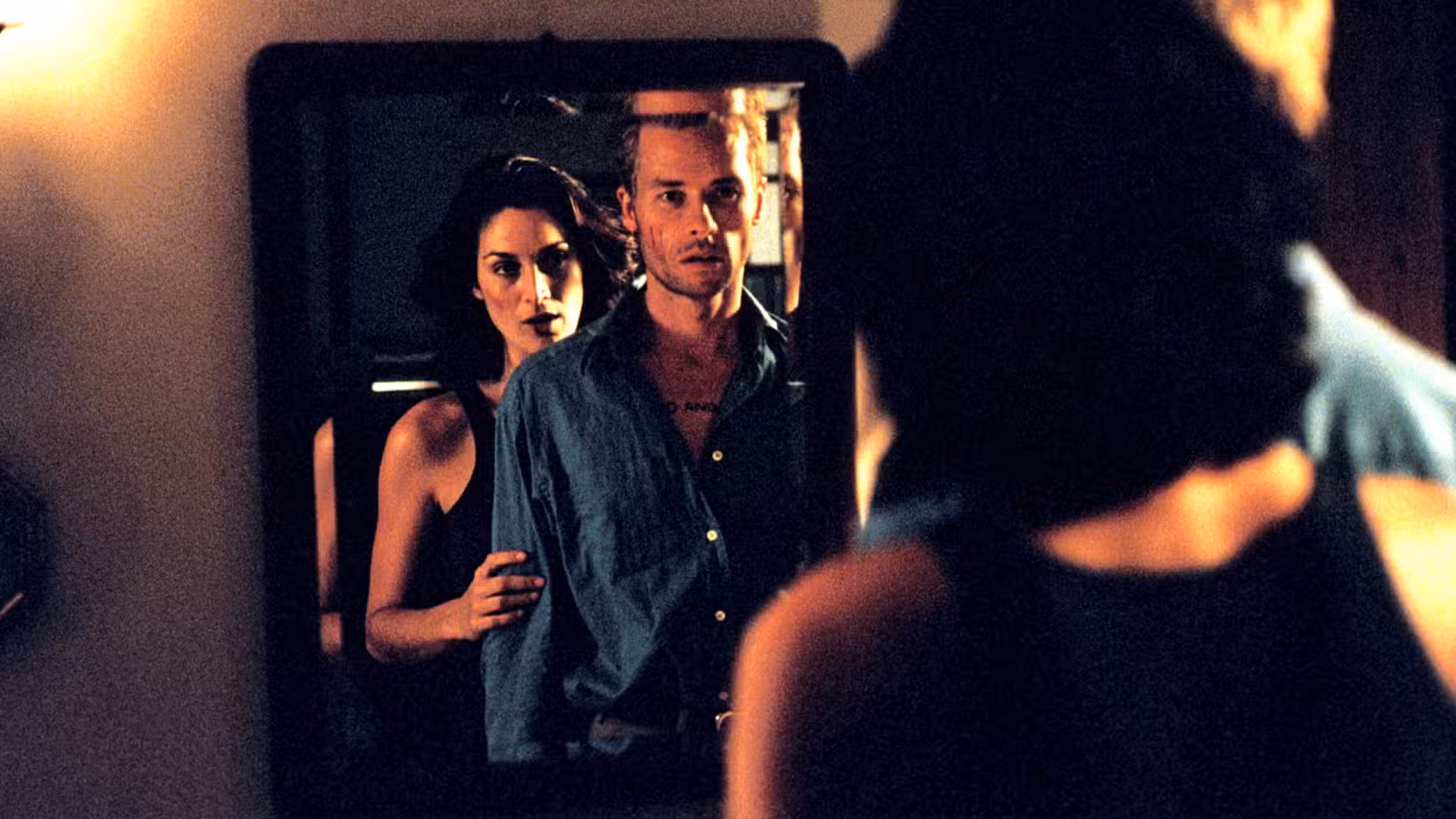 Natalie (Carrie-Anne Moss) fica atrás de Leonard (Guy Pearce) na frente de um espelho em Memento