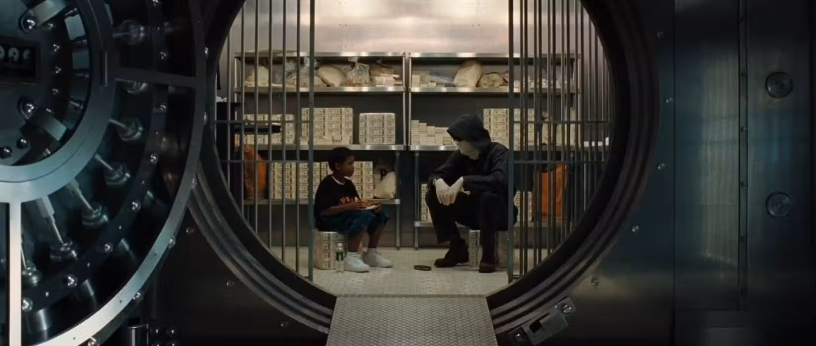 Em uma cena do filme Inside Man, filmada à distância, um ladrão de banco interpretado por Clive Owen está sentado em um cofre de banco e conversa com um adolescente. Eles ficam voltados um para o outro no centro do quadro, com a abertura circular para o valor que os rodeia e enquadra ainda mais a imagem.