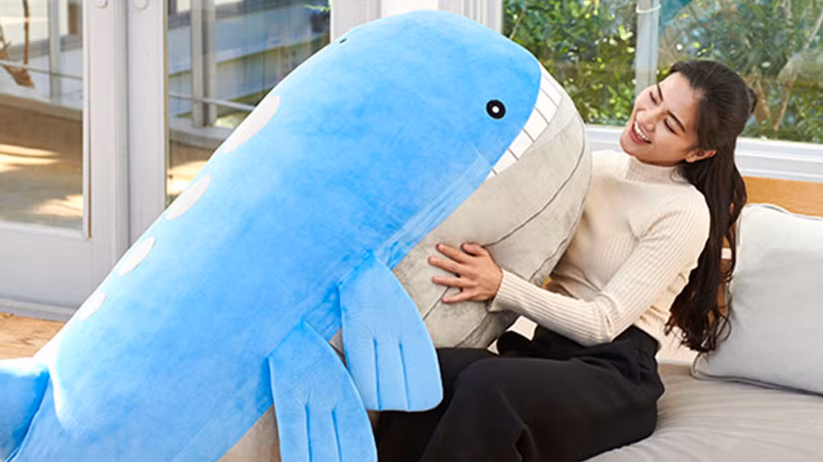 Pelúcia Wailord no colo de uma mulher