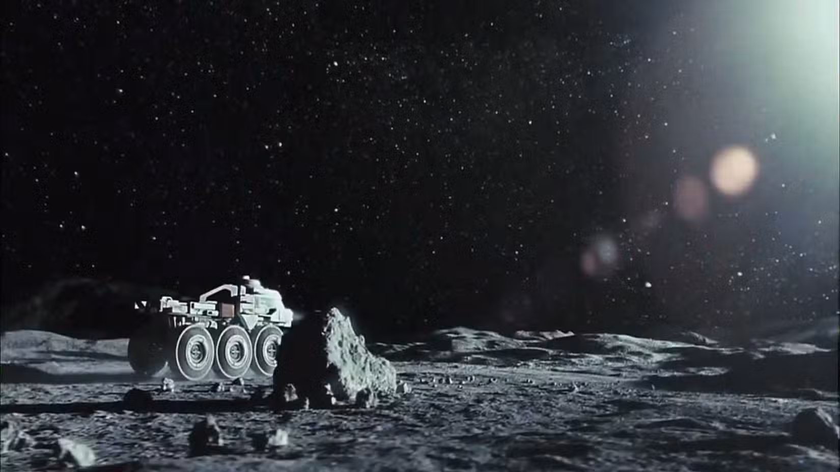 Quadro do filme Lua apresentando um veículo lunar andando ao longo da superfície da lua. 
