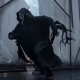 Ghostface, o assassino vestido de preto e máscara branca da franquia Pânico, corre atrás de alguém contra o pano de fundo de telas brancas sustentadas por andaimes pretos em Pânico VI