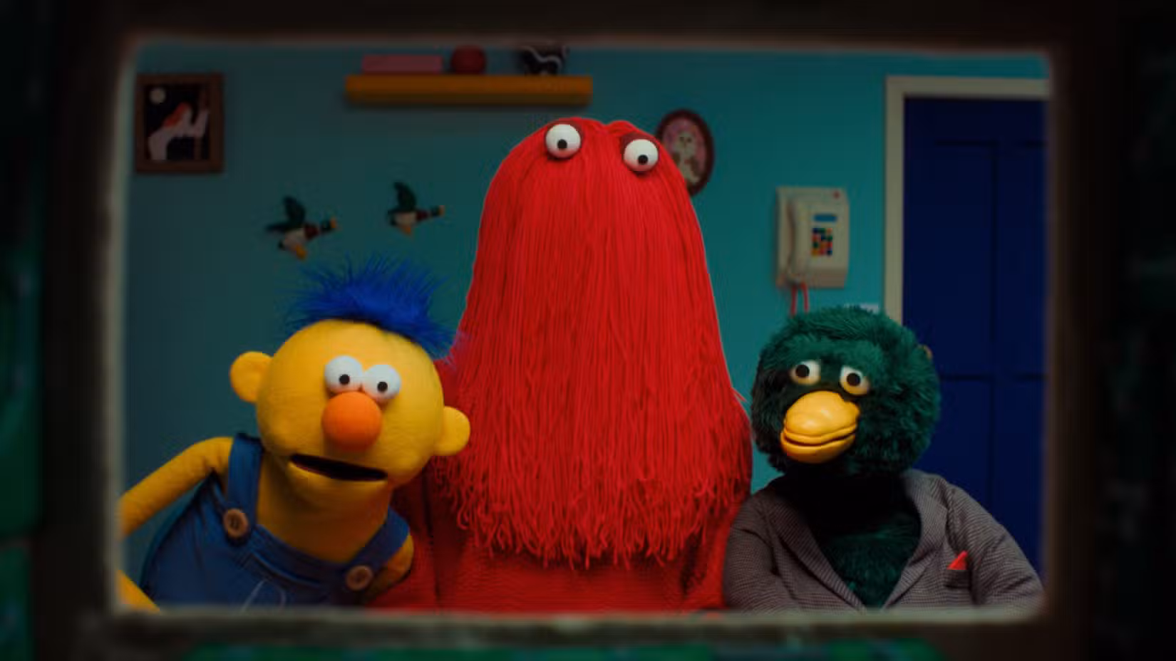 Yellow Guy, Red Guy e Duck de Don't Hug Me I'm Scared olhando através da moldura de uma televisão.