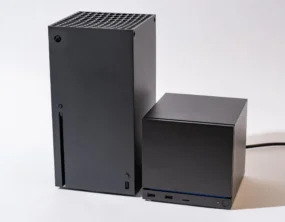 An Xbox Series X next to a Steam Machine. The Steam Machine is roughly half the size of the Series X.