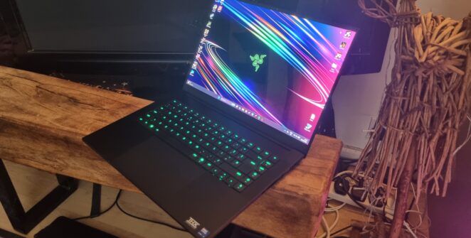 A Razer Blade 16 gaming laptop in front of a TV next to a wooden sculpture