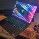 A Razer Blade 16 gaming laptop in front of a TV next to a wooden sculpture