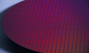 A close-up stylized photo of a silicon wafer, showing many small processor dies